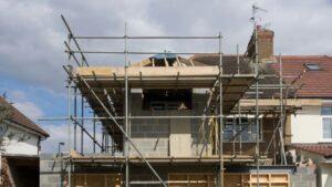 Woning in aanbouw met steigers en open dakconstructie, mogelijk in afwachting van vergunning aanbouw