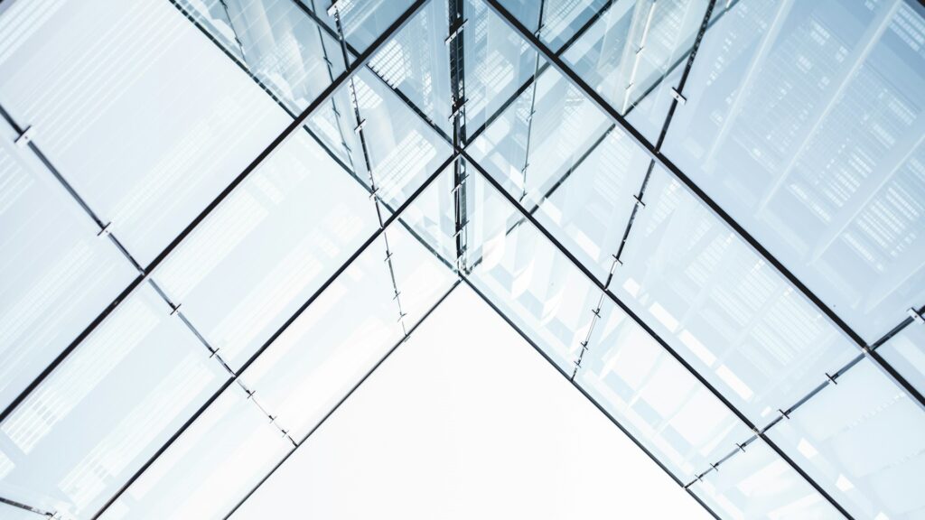 Strakke glazen constructie als dak van een transparante tussenruimte met metalen profielen en lichtinval