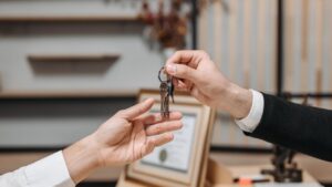 Twee personen wisselen een sleutelbos uit tijdens overdracht van vastgoed of huurcontract
